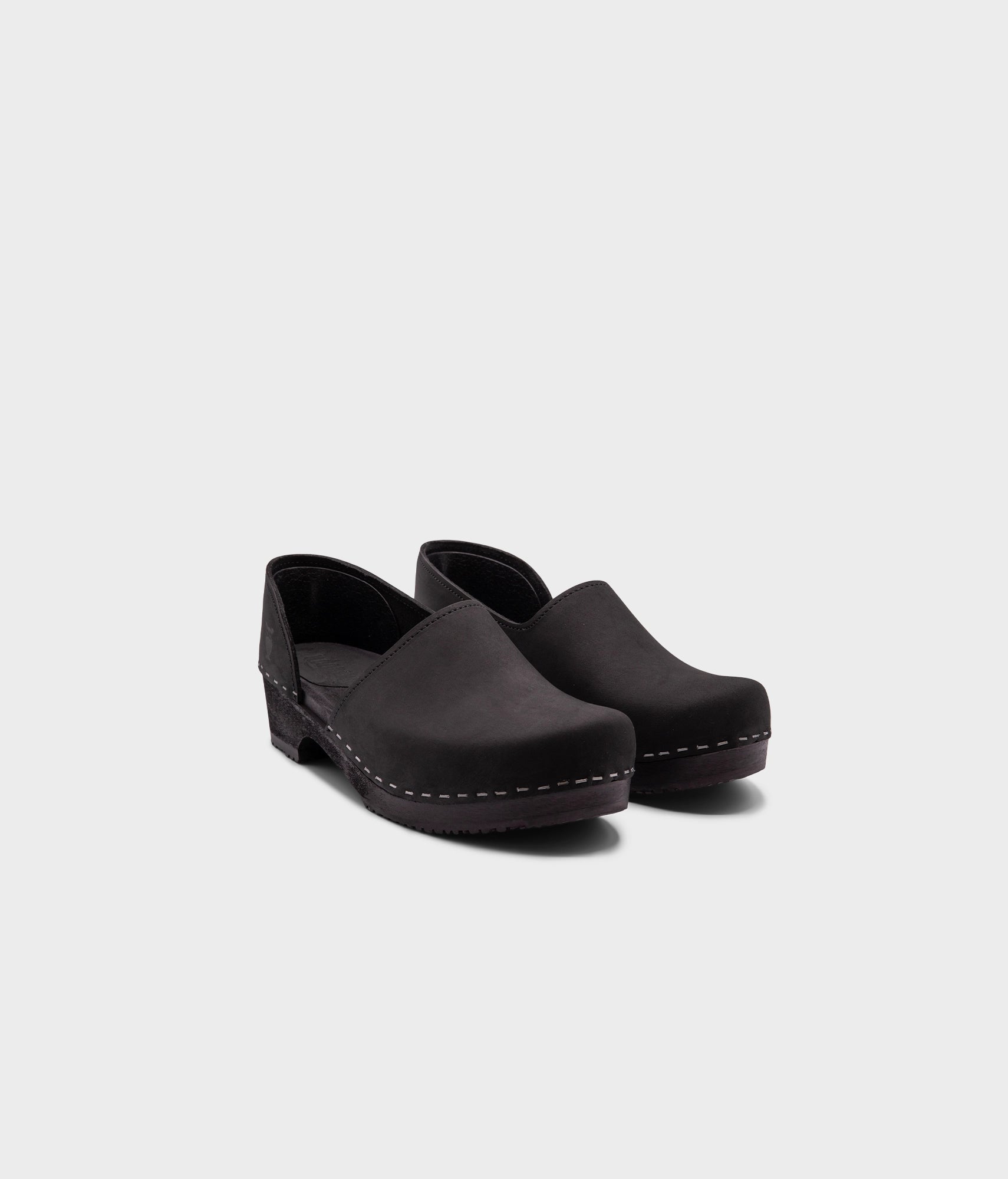 low heeled closed-back clogs in black nubuck leather stapled on a black wooden base