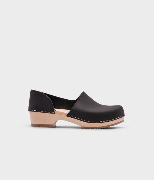 low heeled closed-back clogs in black nubuck leather stapled on a light wooden base