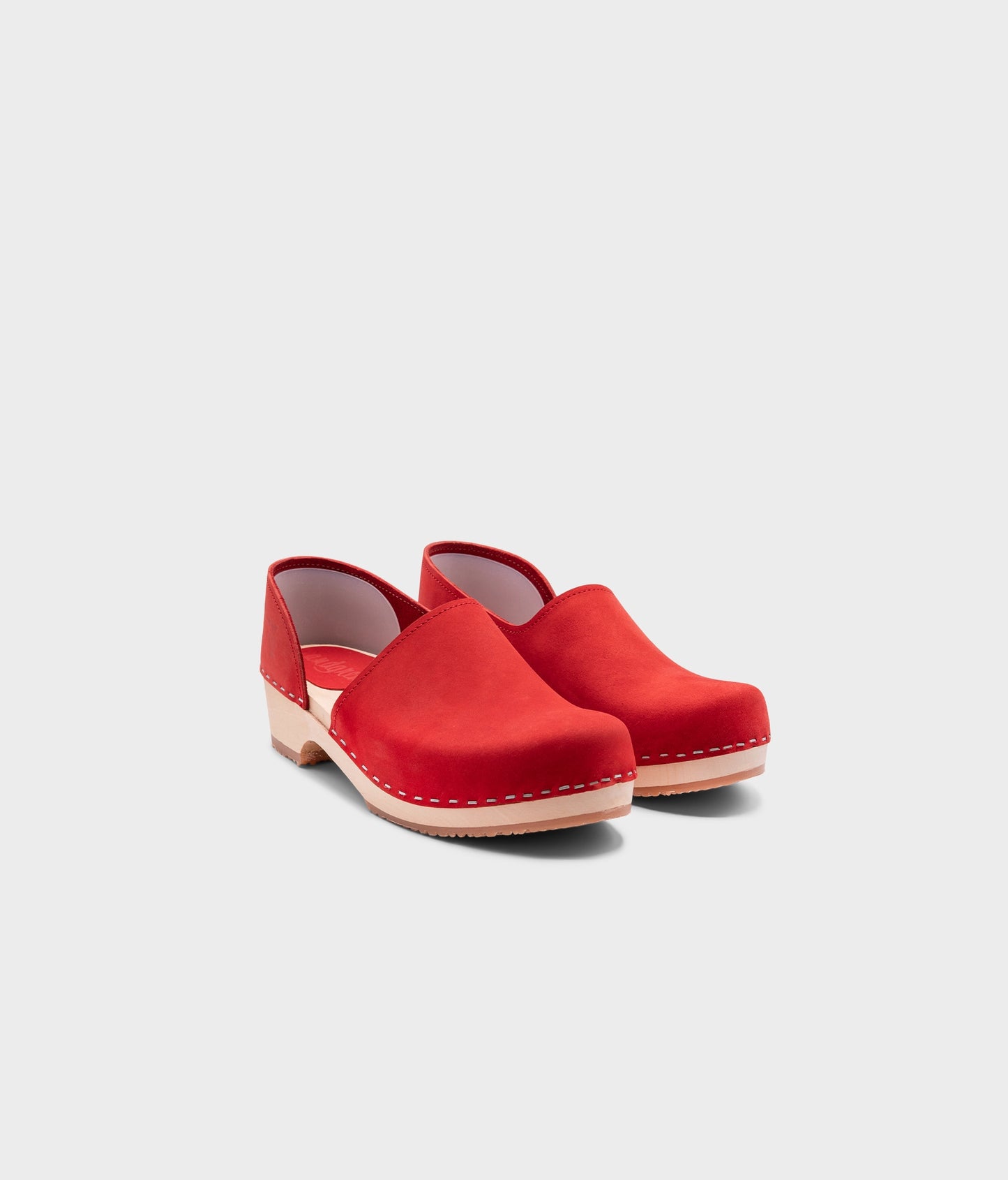 low heeled closed-back clogs in red nubuck leather stapled on a light wooden base