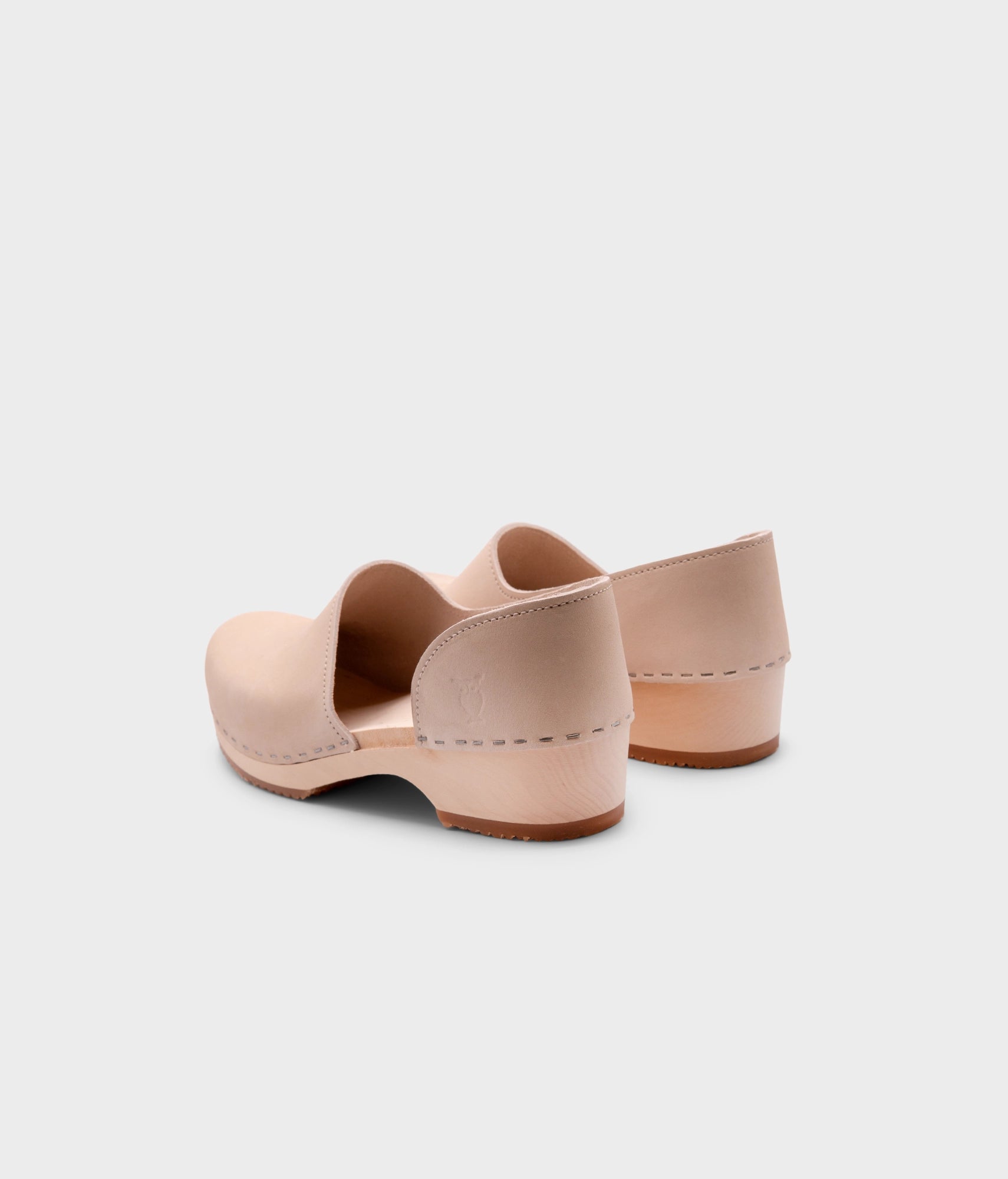 low heeled closed-back clogs in sand white nubuck leather stapled on a light wooden base