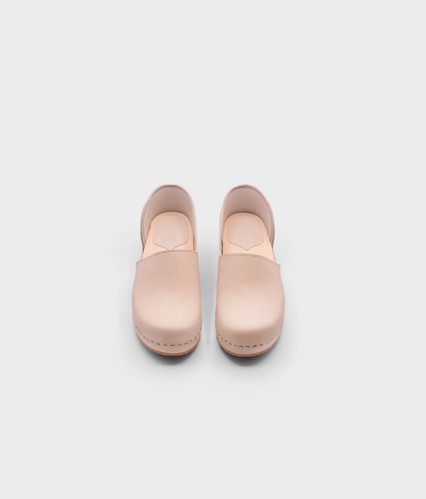 low heeled closed-back clogs in sand white nubuck leather stapled on a light wooden base