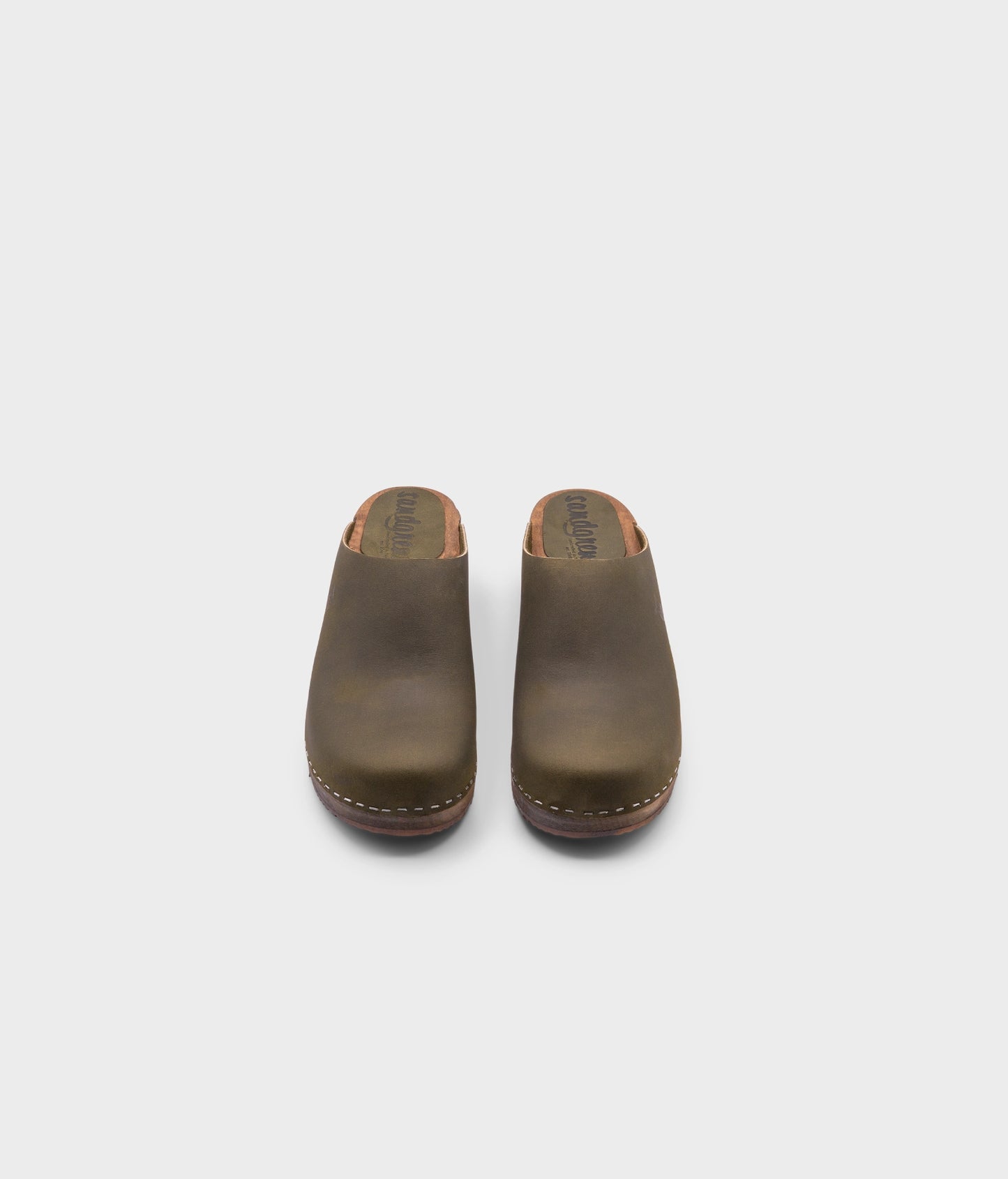 low heeled minimalistic clog mules in olive nubuck leather stapled on a dark wooden base