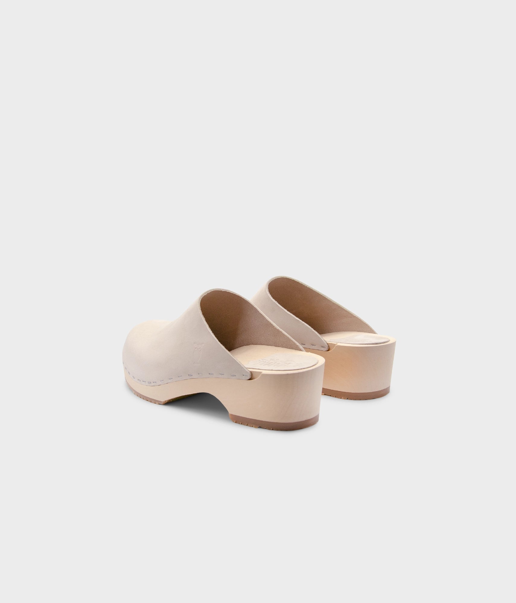 low heeled minimalistic clog mules in sand white nubuck leather stapled on a light wooden base