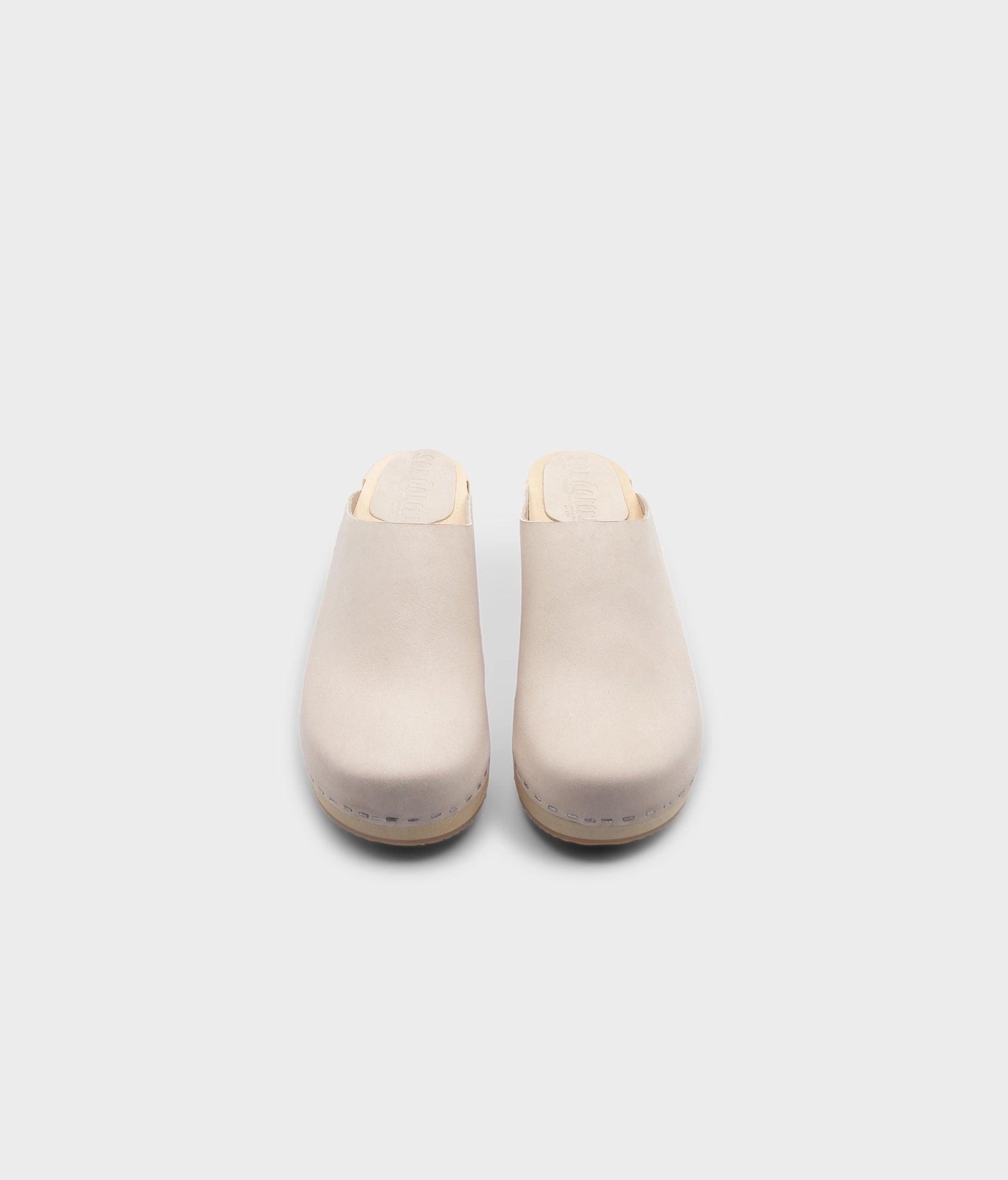 low heeled minimalistic clog mules in sand white nubuck leather stapled on a light wooden base