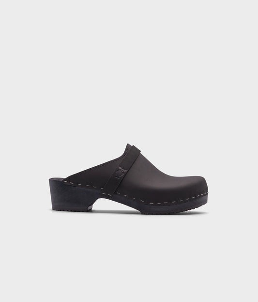 classic low heeled clog mule in black nubuck leather stapled on a black wooden base with a leather strap