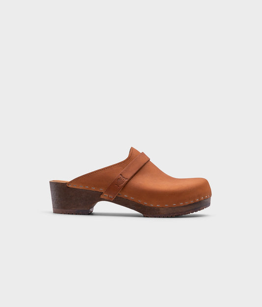 classic low heeled clog mule in light brown nubuck leather stapled on a dark wooden base with a leather strap