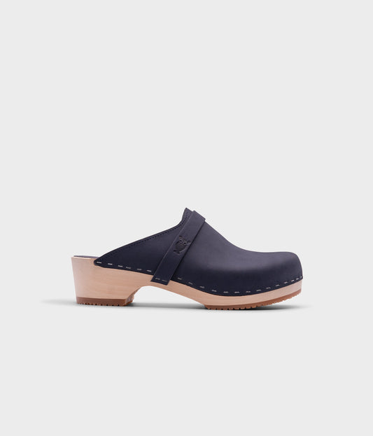 classic low heeled clog mule in navy blue nubuck leather stapled on a light wooden base with a leather strap