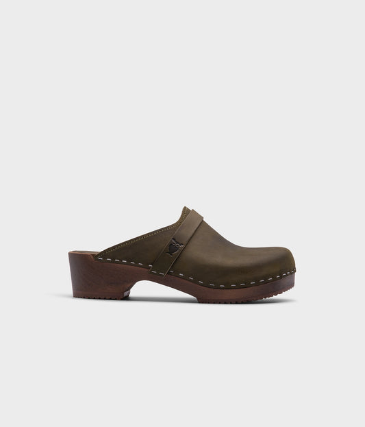 classic low heeled clog mule in olive green nubuck leather stapled on a dark wooden base with a leather strap