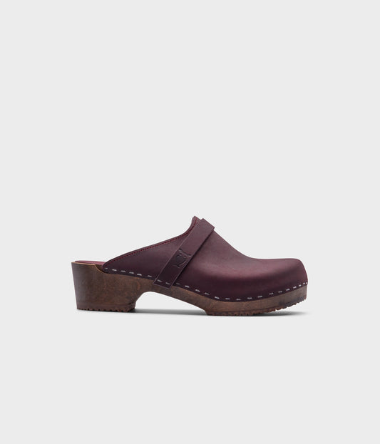 classic low heeled clog mule in plum purple nubuck leather stapled on a dark wooden base with a leather strap