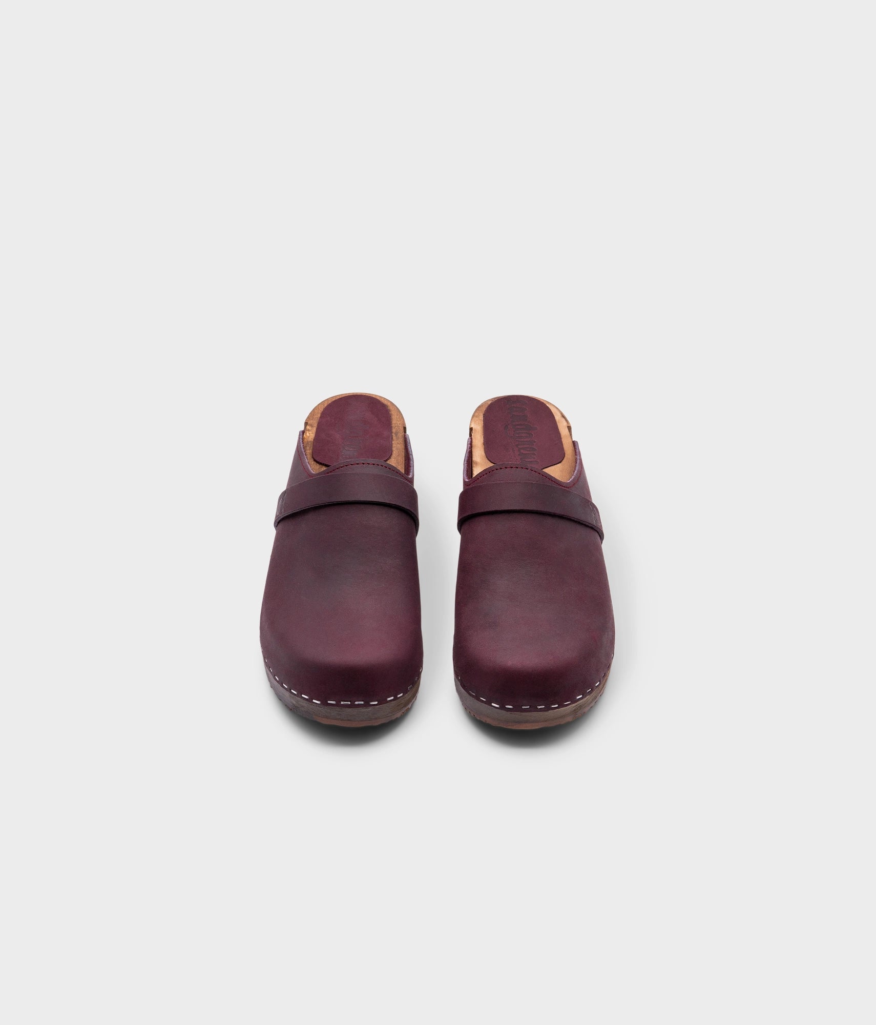 classic low heeled clog mule in plum purple nubuck leather stapled on a dark wooden base with a leather strap