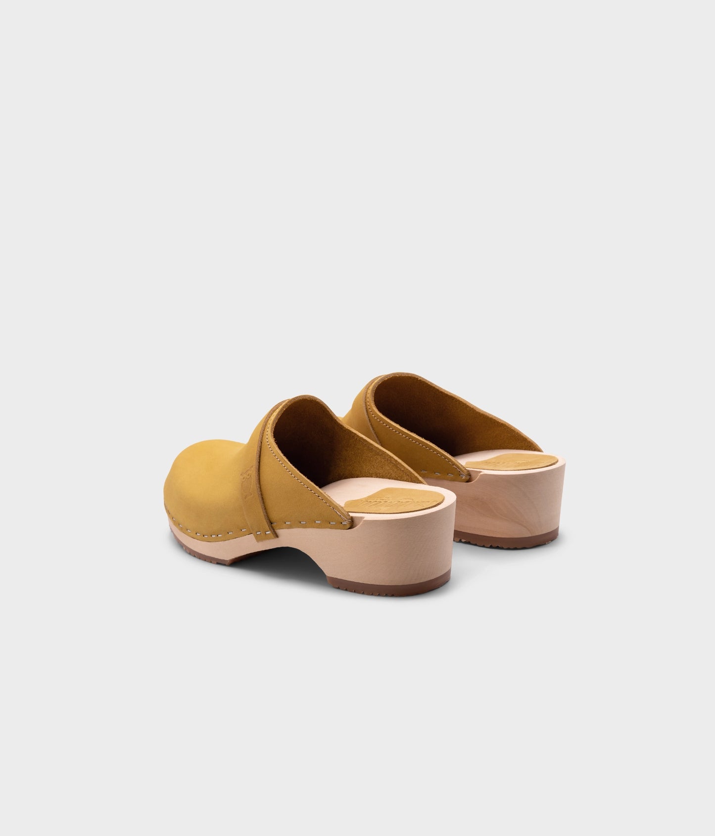 classic low heeled clog mule in yellow nubuck leather stapled on a light wooden base with a leather strap