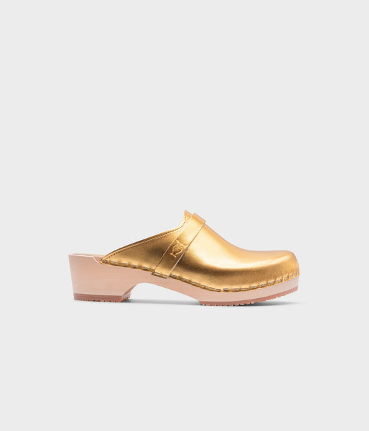 classic low heeled clog mule in metallic gold traditional leather stapled on a light wooden base with a leather strap