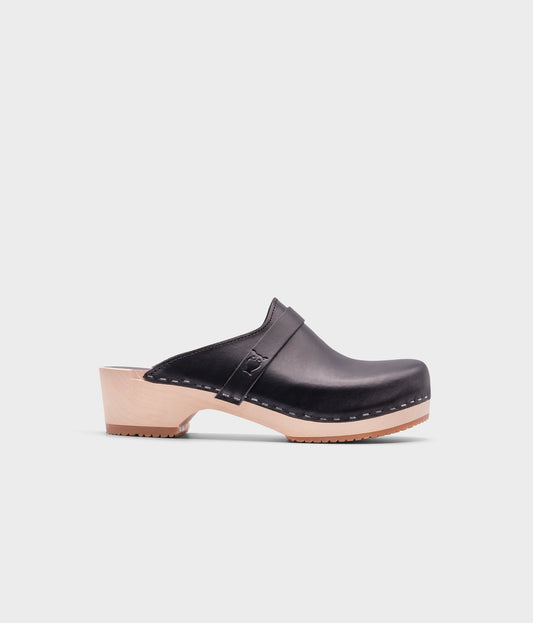 classic low heeled clog mule in black vegetable tanned leather stapled on a light wooden base with a leather strap