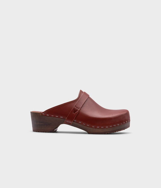 classic low heeled clog mule in cognac red vegetable tanned leather stapled on a dark wooden base with a leather strap