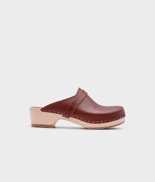 classic low heeled clog mule in cognac red vegetable tanned leather stapled on a light wooden base with a leather strap