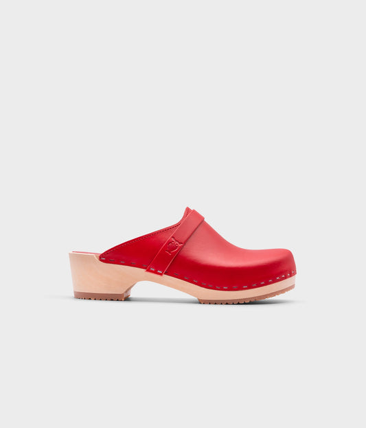 classic low heeled clog mule in red vegetable tanned leather stapled on a light wooden base with a leather strap