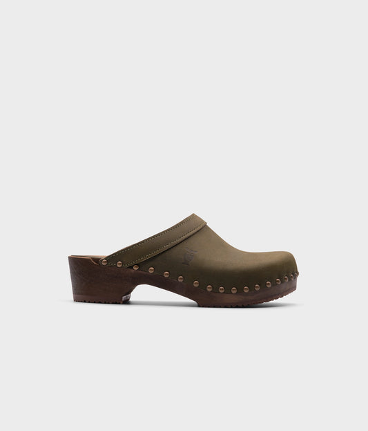 low heeled clog mules in olive nubuck leather stapled on a dark wooden base with brass gold studs