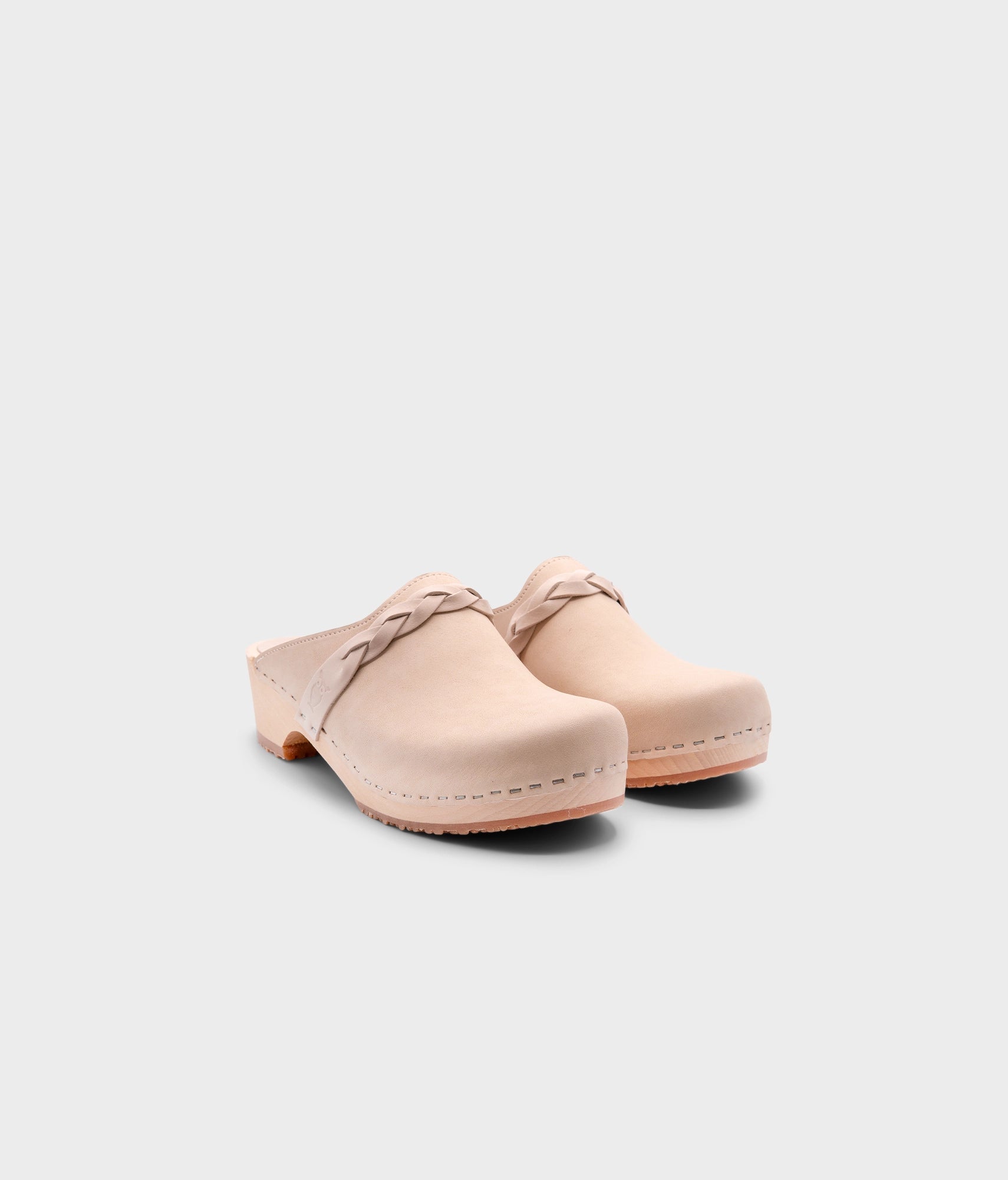 low heeled clog mules in sand white nubuck leather with a braided strap stapled on a light wooden base