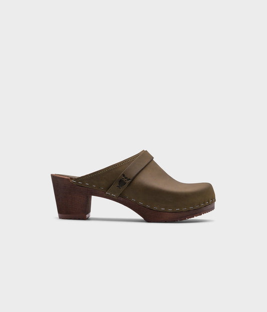 classic high heeled clog mule in olive green nubuck leather stapled on a dark wooden base with a leather strap