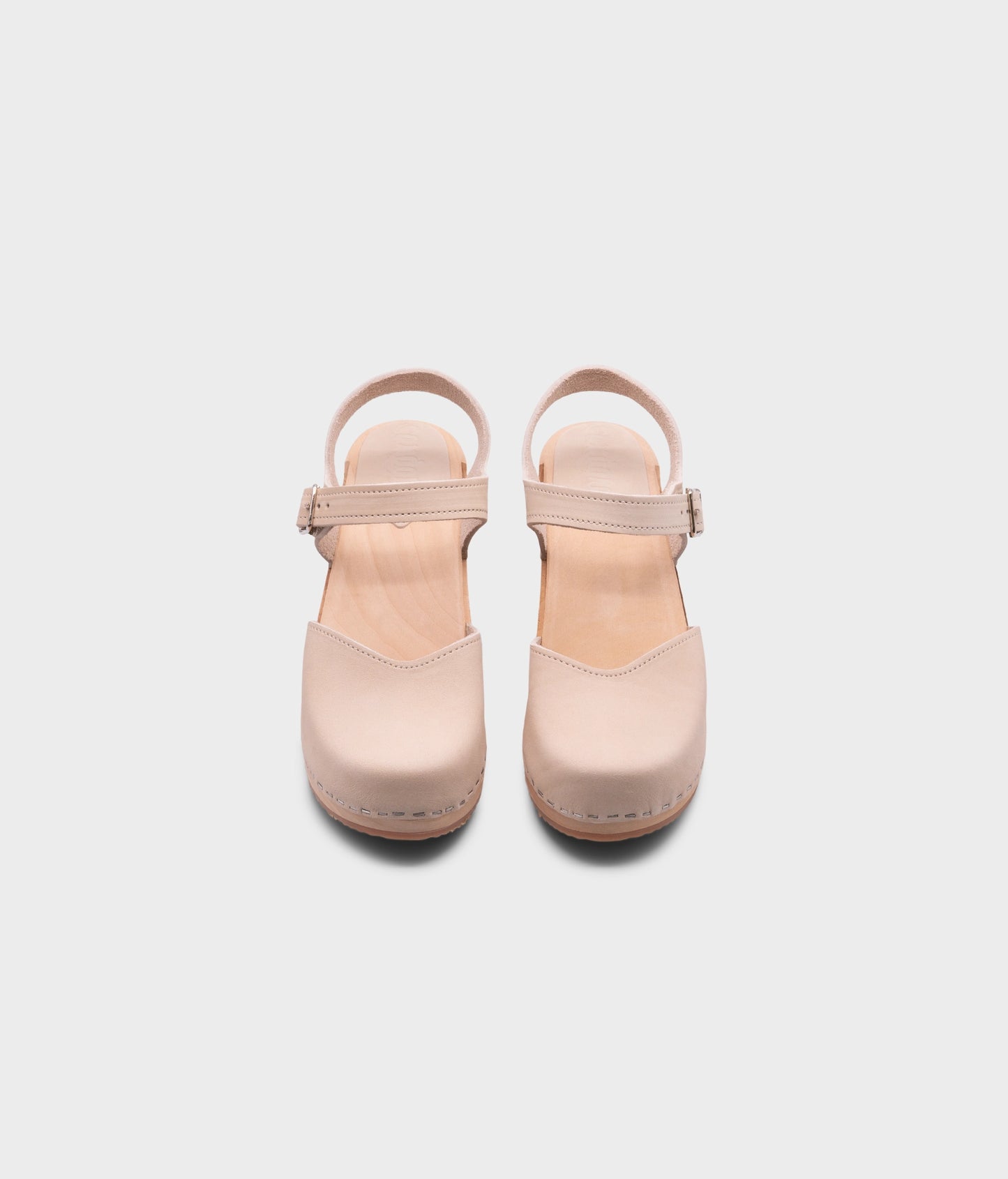 high heeled closed-toe clog sandal in sand white nubuck leather stapled on a light wooden base