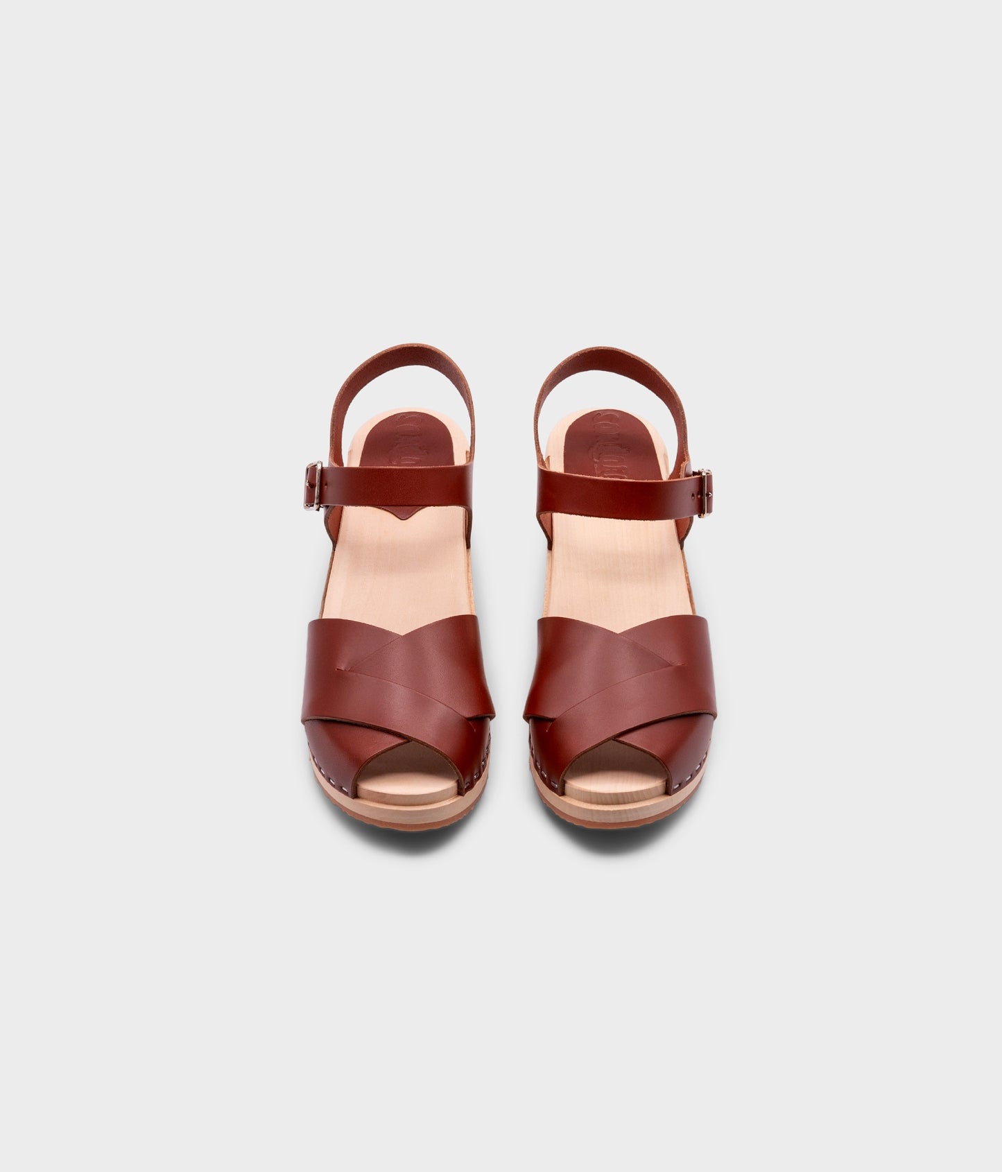 high heeled clog sandals in cognac red vegetable tanned leather with an open-toe stapled on a light wooden base