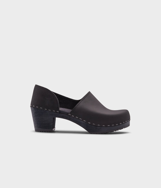high heeled closed-back clogs in black nubuck leather stapled on a black wooden base
