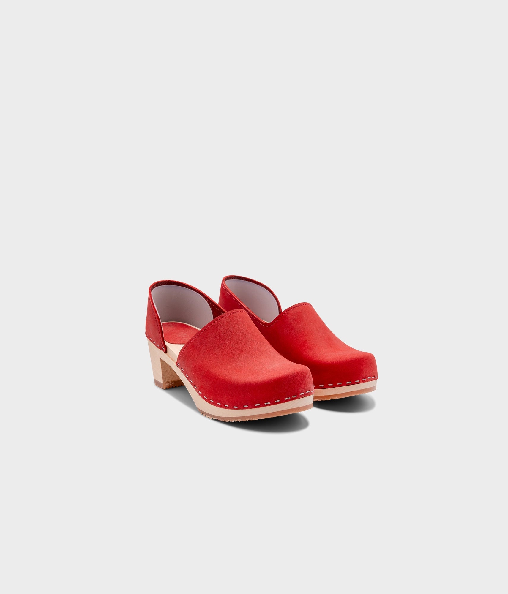 high heeled closed-back clogs in red nubuck leather stapled on a light wooden base