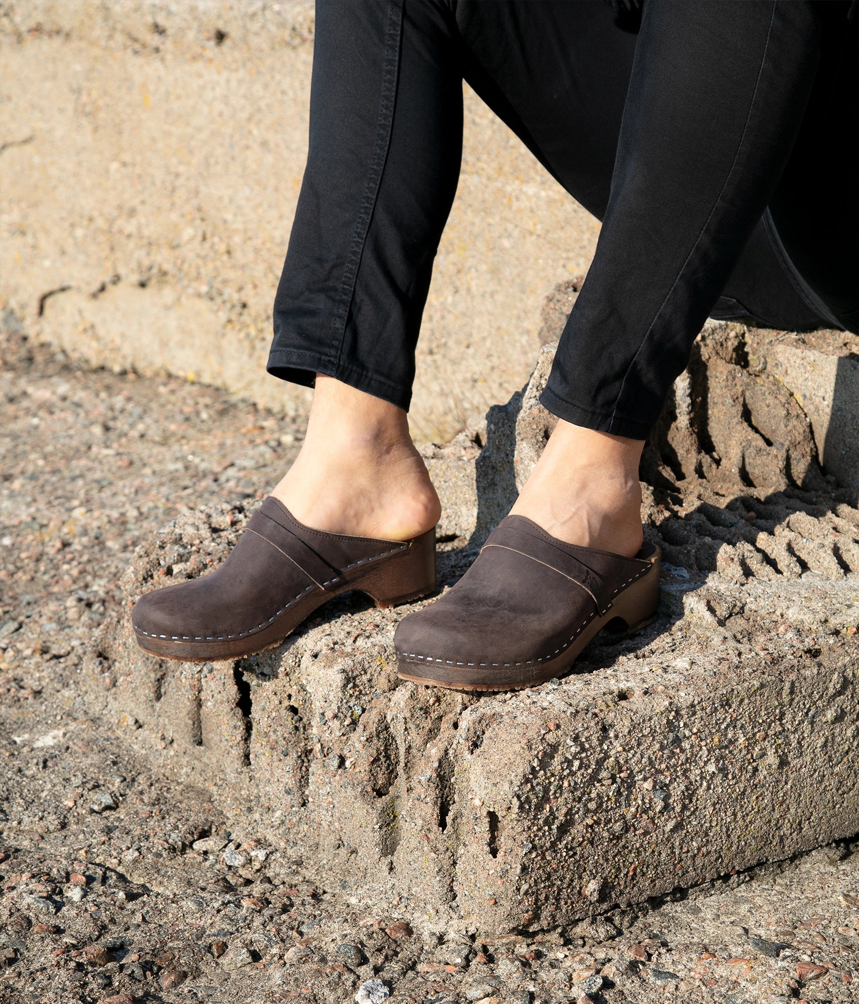 low heeled classic clog mules in dark brown nubuck leather stapled on a dark wooden base