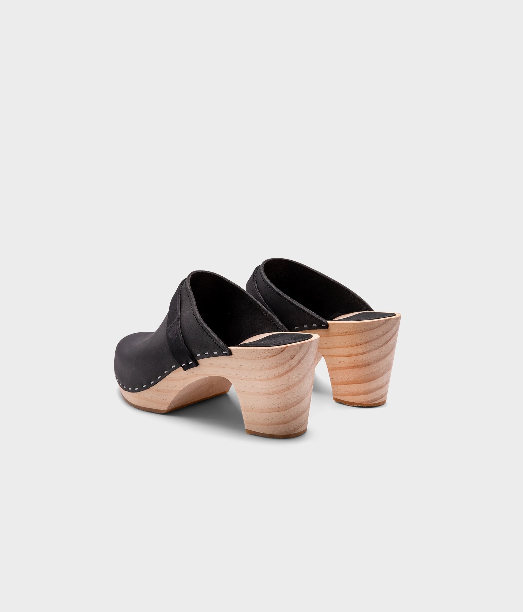 classic high rise heel clog mule in black nubuck leather stapled on a light wooden base