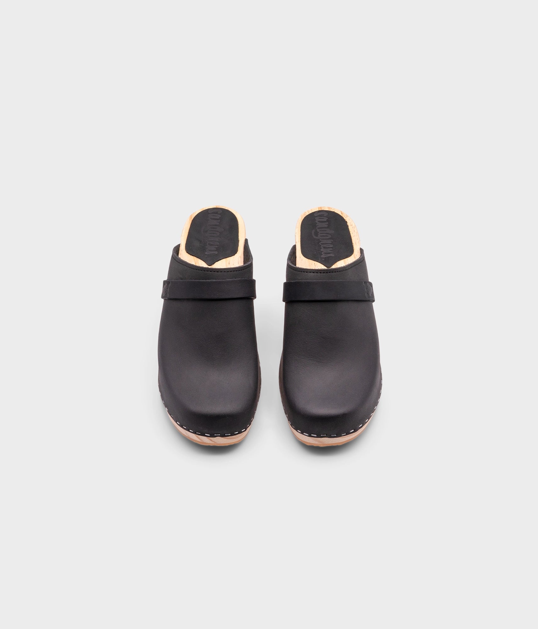 classic high rise heel clog mule in black nubuck leather stapled on a light wooden base