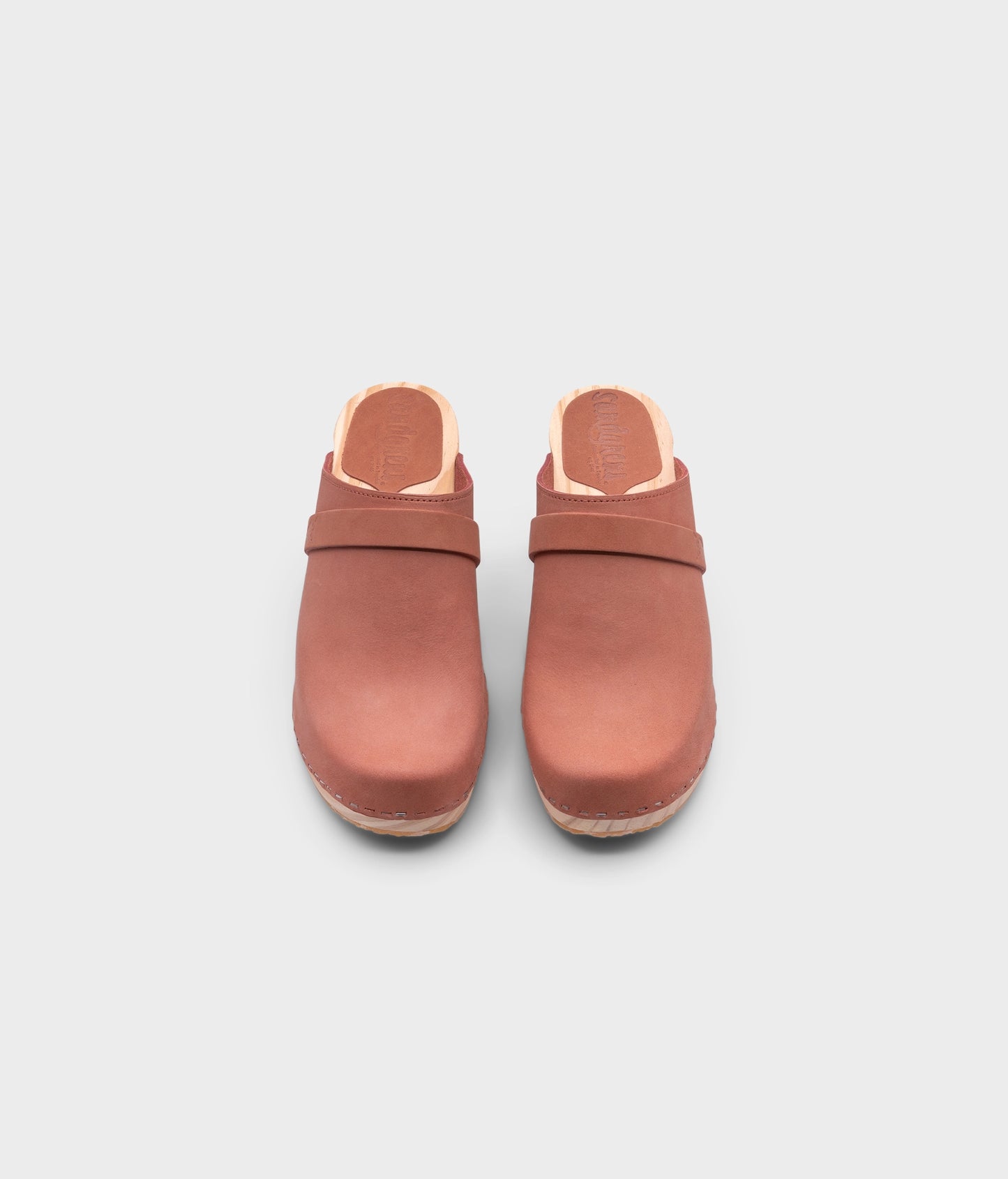 classic high rise heel clog mule in blush pink nubuck leather stapled on a light wooden base