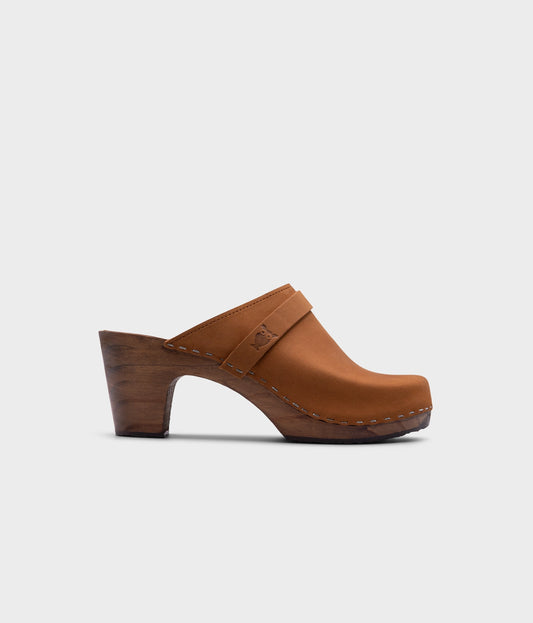 classic high rise heel clog mule in light brown nubuck leather stapled on a dark wooden base
