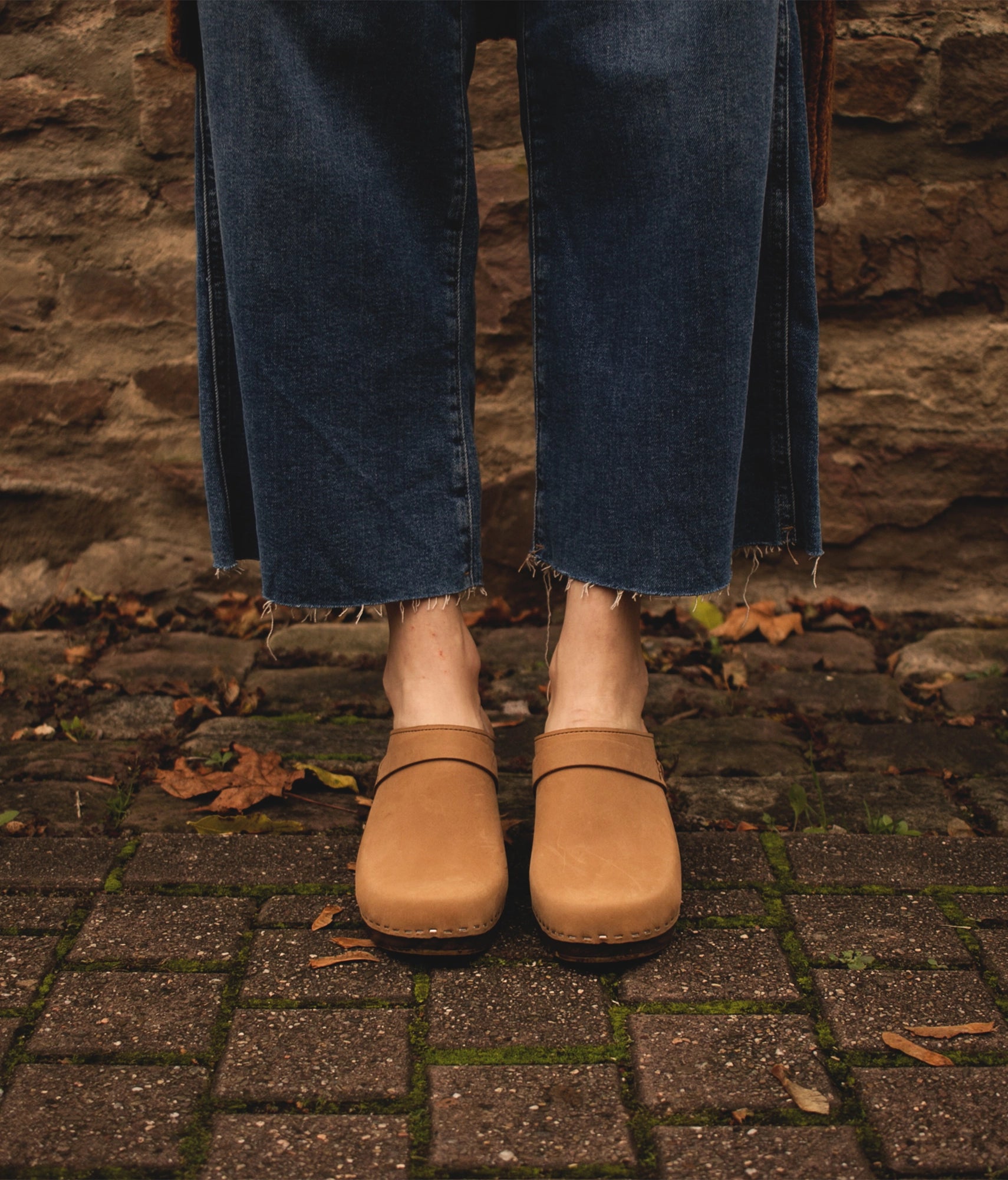 classic high rise heel clog mule in light brown nubuck leather stapled on a dark wooden base