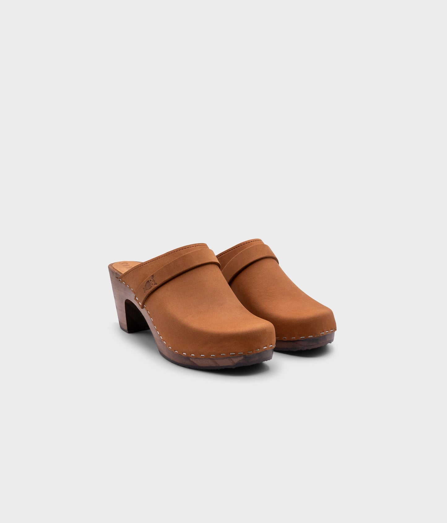 classic high rise heel clog mule in light brown nubuck leather stapled on a dark wooden base