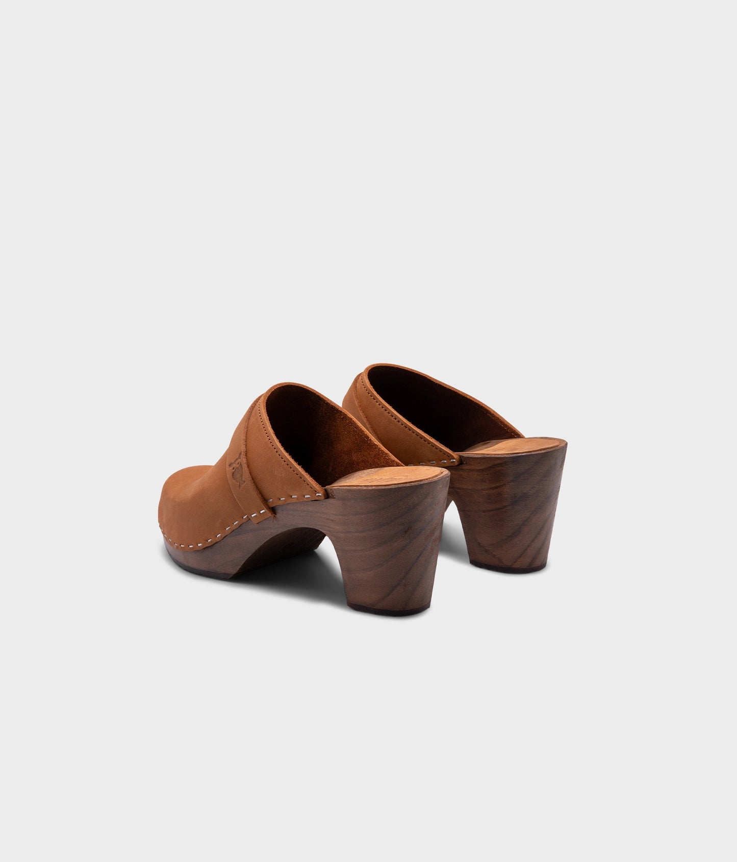 classic high rise heel clog mule in light brown nubuck leather stapled on a dark wooden base