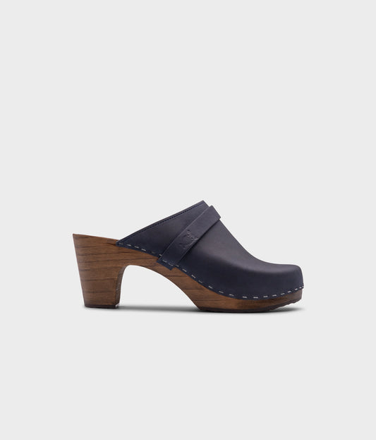 classic high rise heel clog mule in navy blue nubuck leather stapled on a dark wooden base