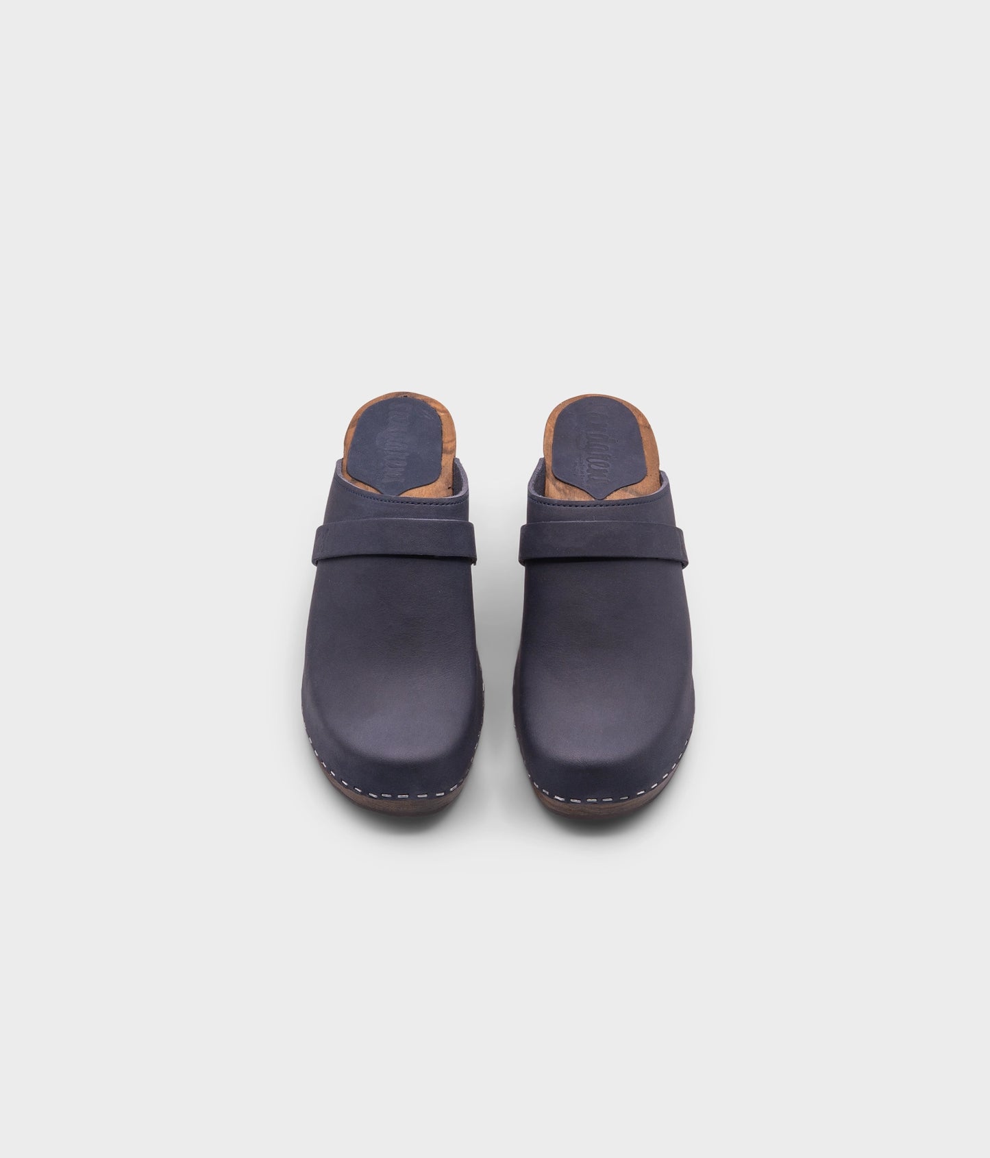 classic high rise heel clog mule in navy blue nubuck leather stapled on a dark wooden base