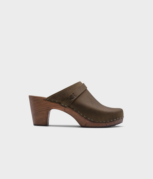 classic high rise heel clog mule in olive green nubuck leather stapled on a dark wooden base