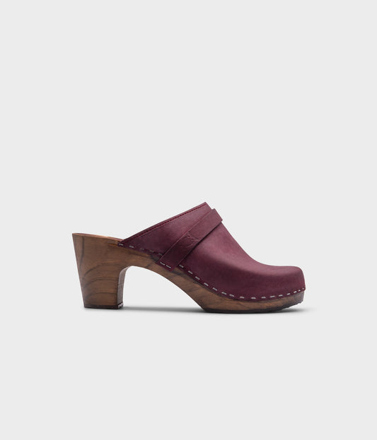classic high rise heel clog mule in dark purple nubuck leather stapled on a dark wooden base