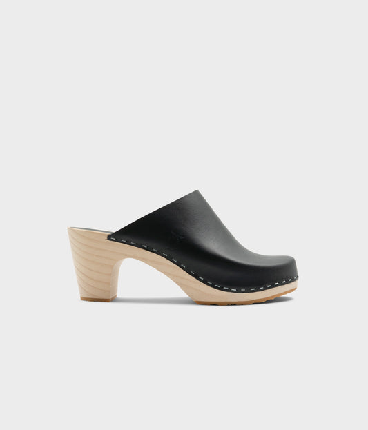 high rise minimalistic clog mule in black vegetable tanned leather stapled on a light wooden base