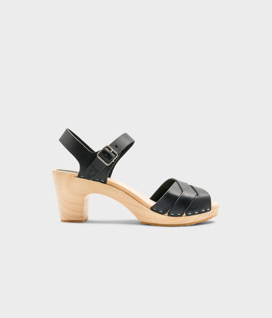 High rise heel clog sandals in black vegetable tanned leather stapled on a light wooden base with an open toe