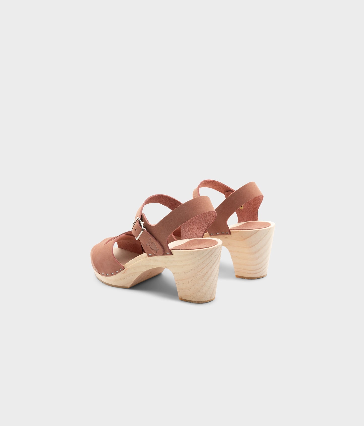 high rise heel crossed clog sandals in blush pink nubuck leather stapled on a light wooden base