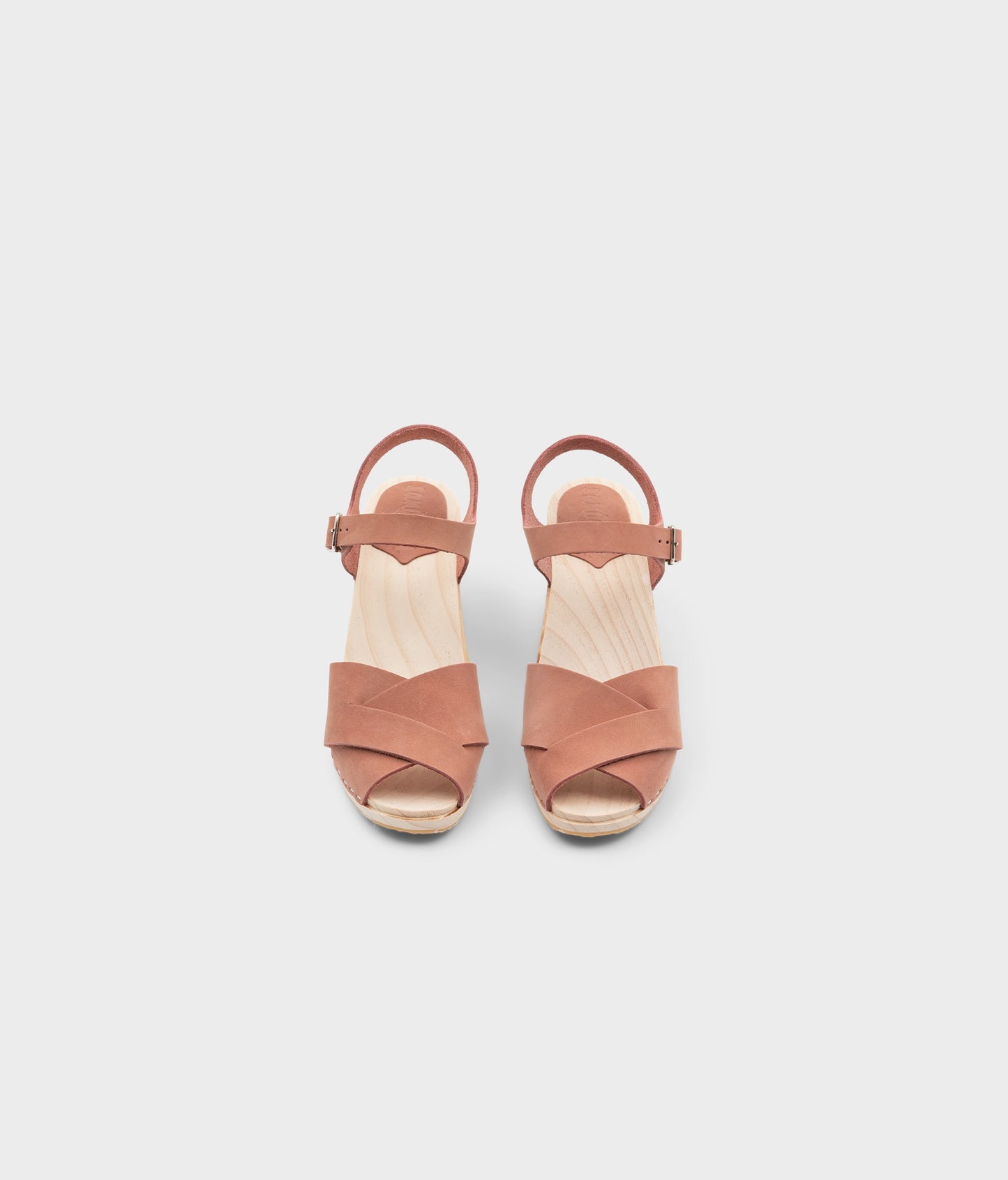 high rise heel crossed clog sandals in blush pink nubuck leather stapled on a light wooden base