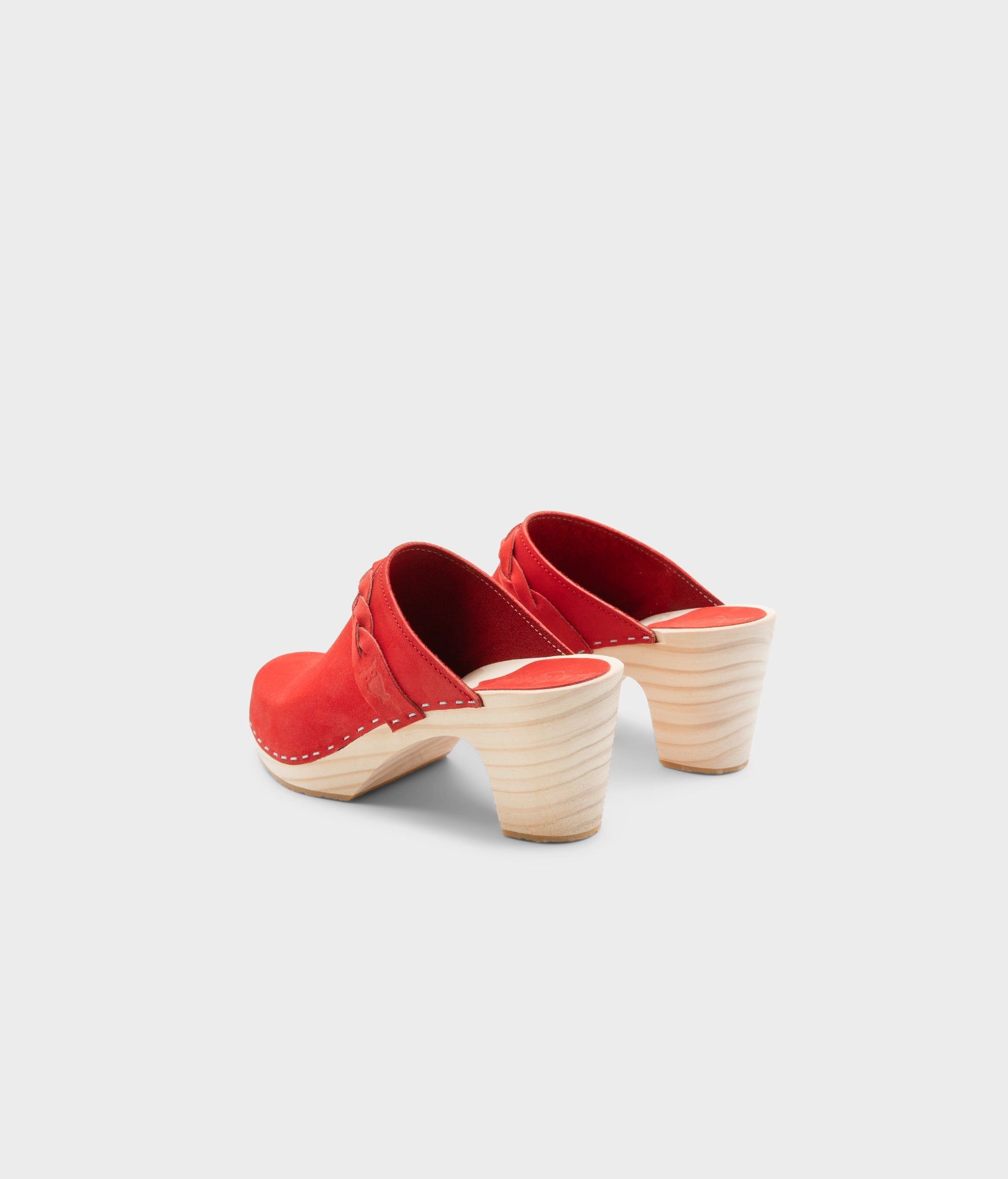 high rise heel braided clog mule in red leather stapled on a light wooden base