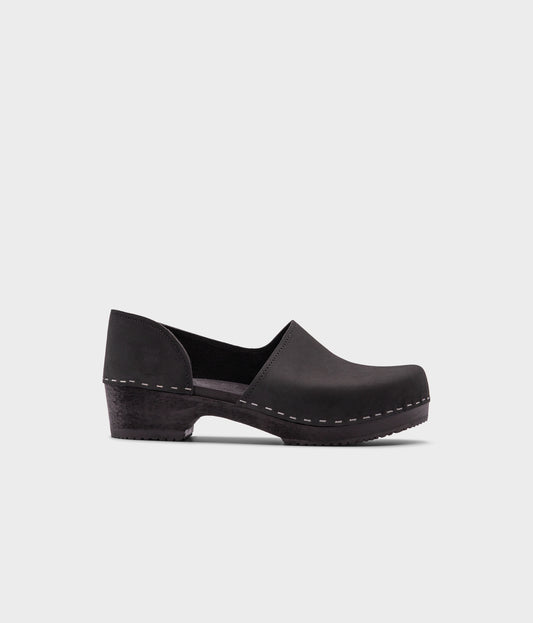 low heeled closed-back clogs in black nubuck leather stapled on a black wooden base
