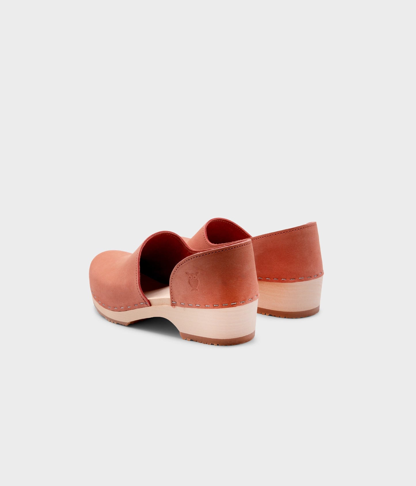 low heeled closed-back clogs in blush pink nubuck leather stapled on a light wooden base