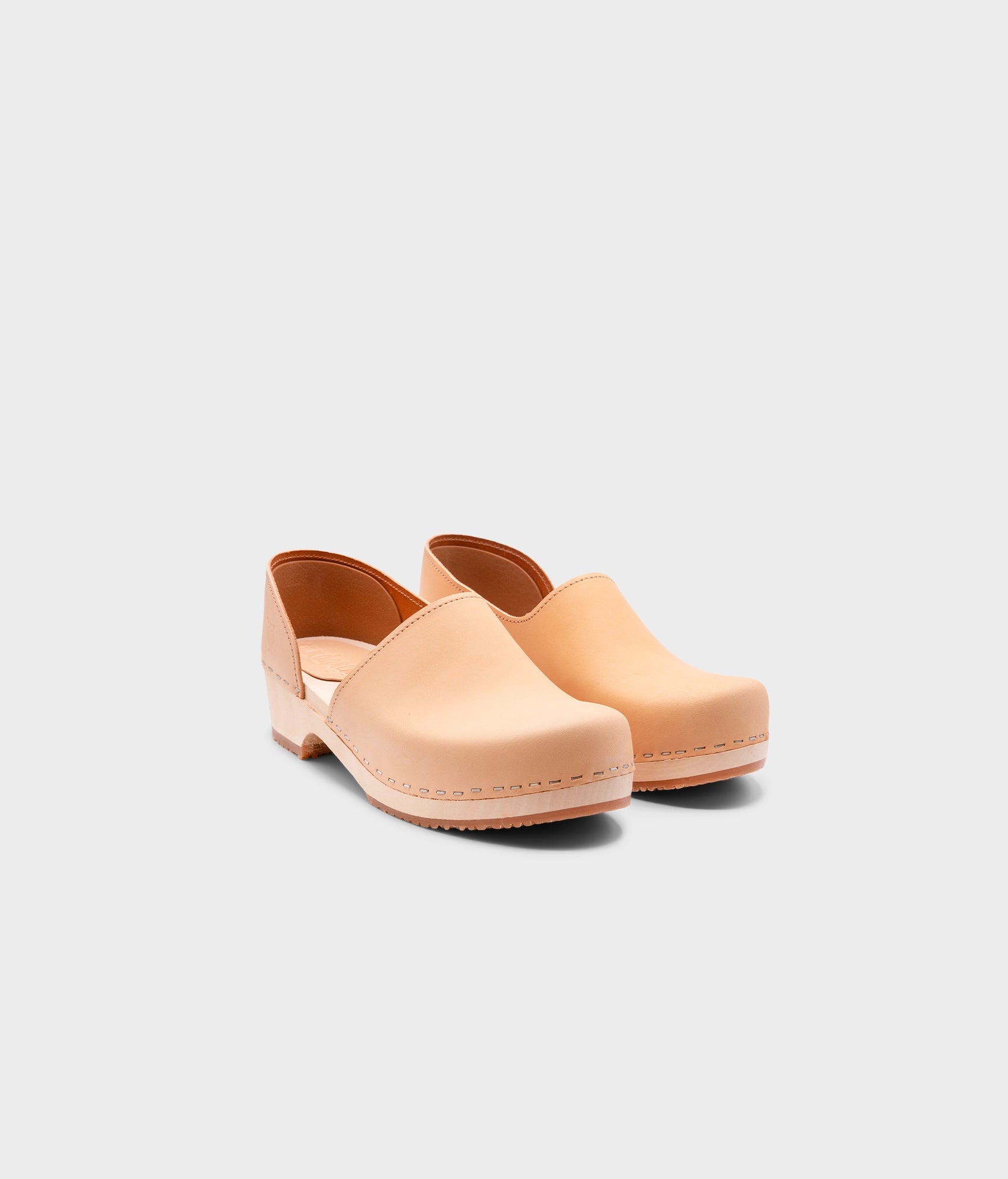 low heeled closed-back clogs in beige vegetable tanned leather stapled on a light wooden base