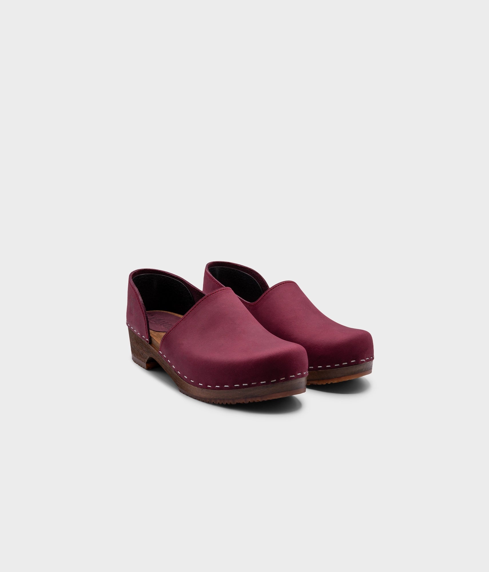 low heeled closed-back clogs in dark purple nubuck leather stapled on a dark wooden base