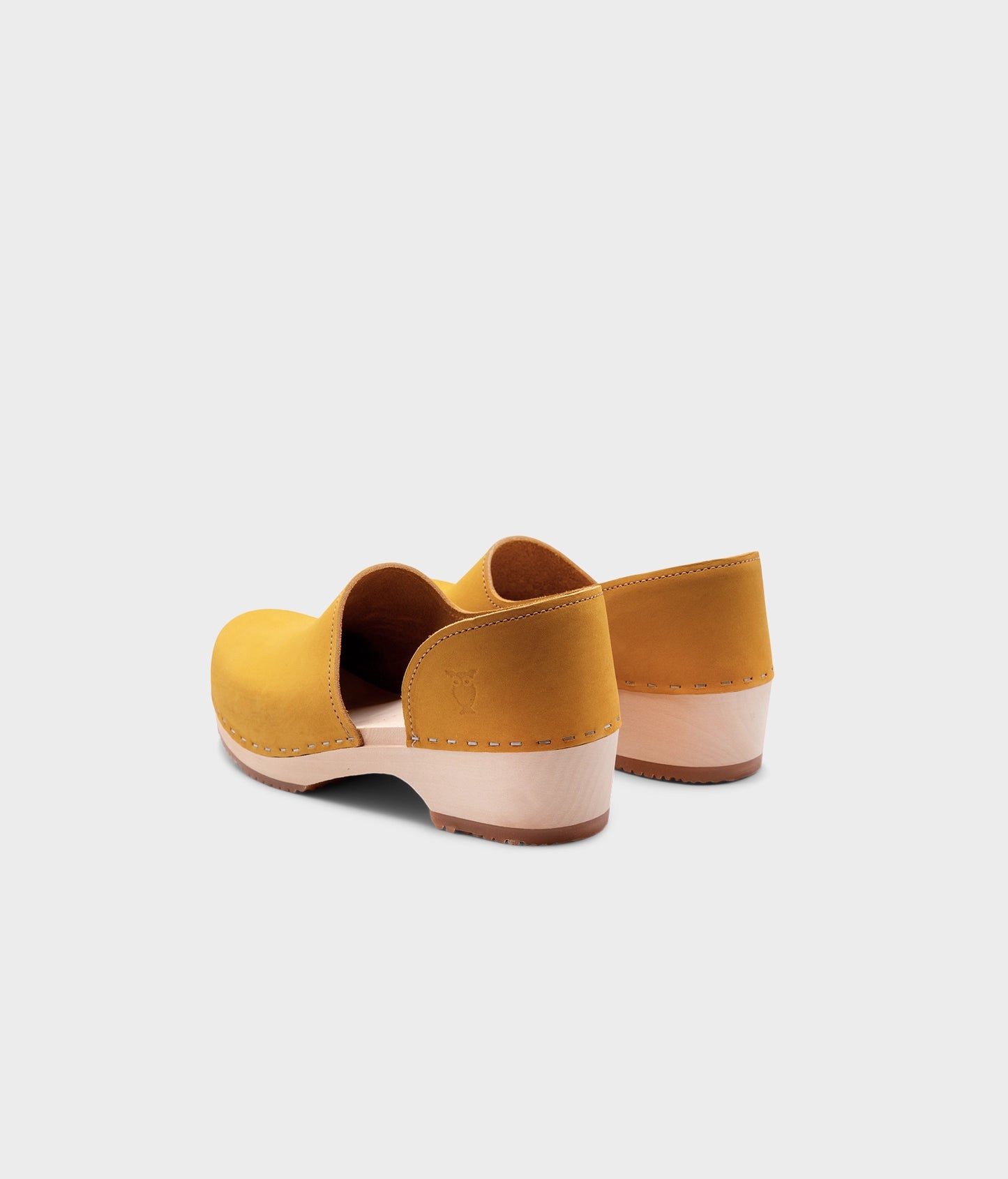low heeled closed-back clogs in yellow nubuck leather stapled on a light wooden base