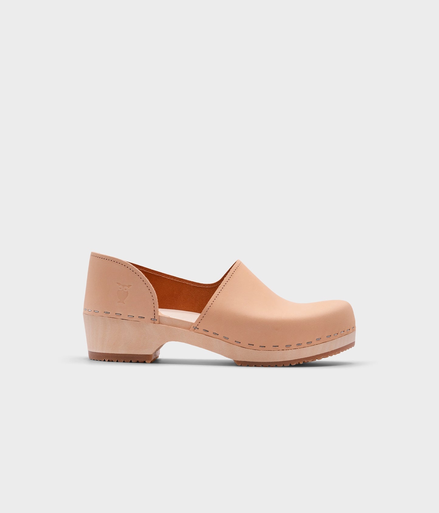 low heeled closed-back clogs in beige vegetable tanned leather stapled on a light wooden base